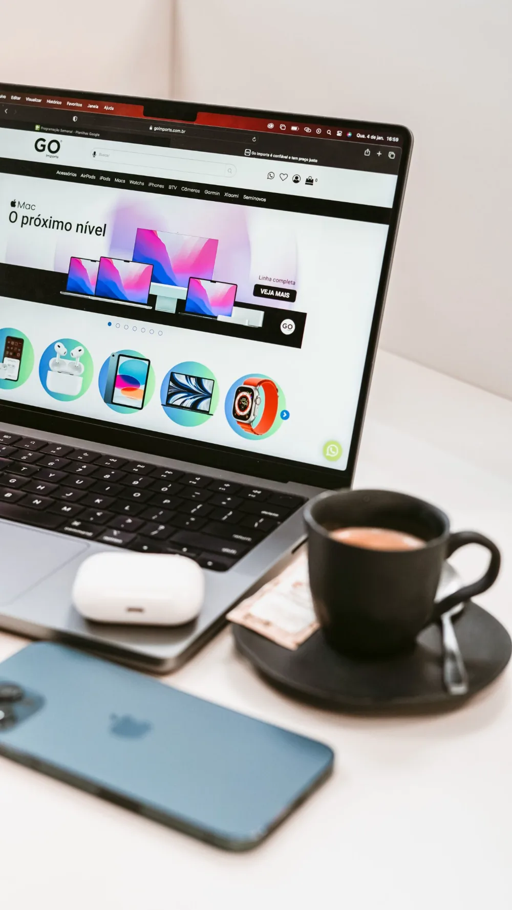 Portátil con una tienda online, teléfono y taza de café sobre una mesa